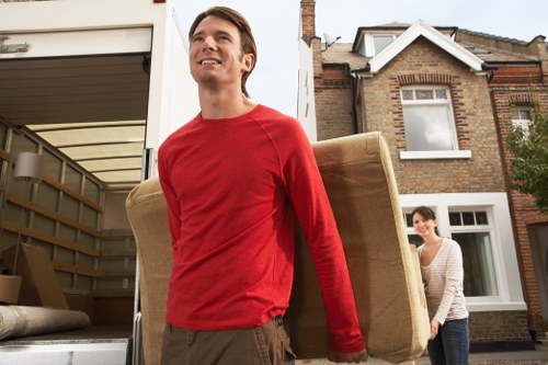 Two movers carrying furniture down apartment hallway in a London flat